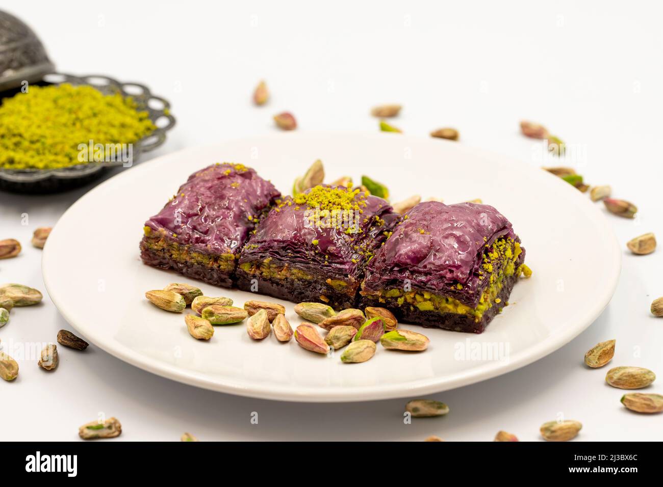 Pistacchio baklava viola su sfondo bianco. Baklava appositamente preparato per i diabetici. Specialità della cucina mediterranea tradizionale. Primo piano Foto Stock