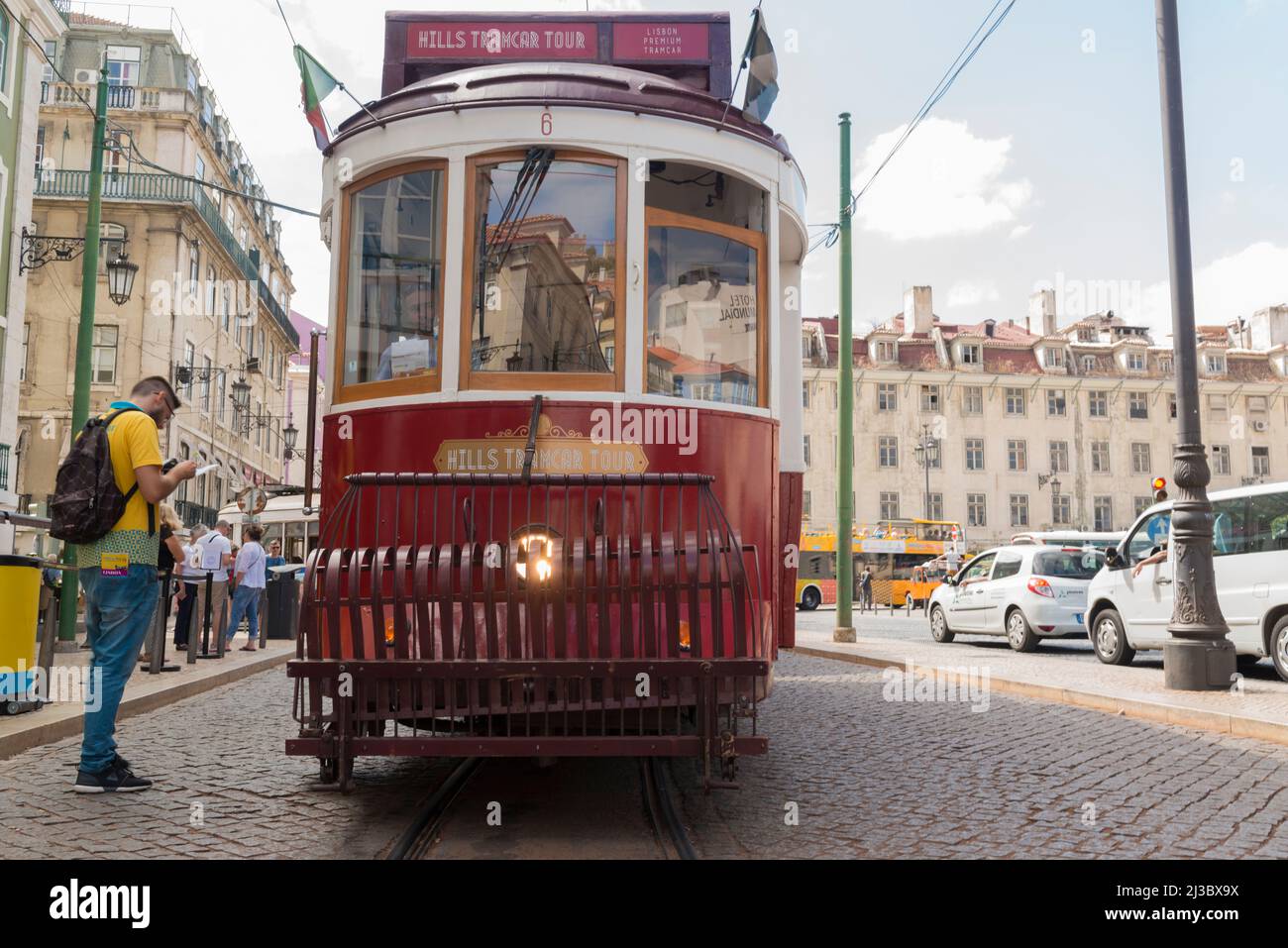 Vista frontale del tram rosso vintage e del turista in camicia gialla nella parte vecchia di Lisbona, Portogallo. Foto Stock