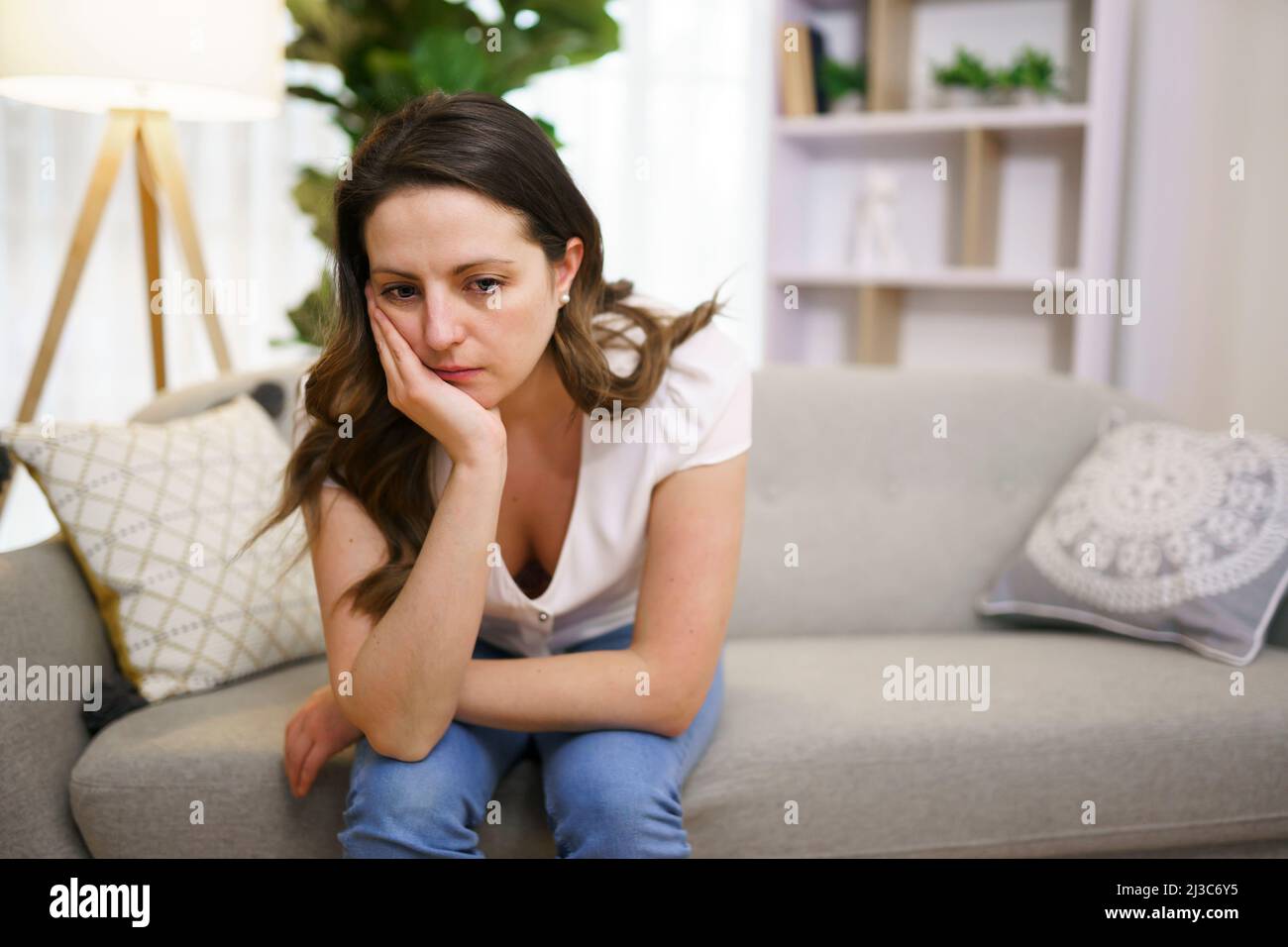 Stressata donna matura seduta sul divano a casa guardare triste Foto Stock