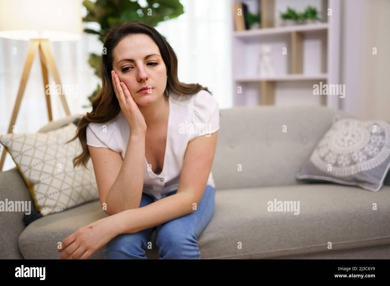 Stressata donna matura seduta sul divano a casa guardare triste Foto Stock