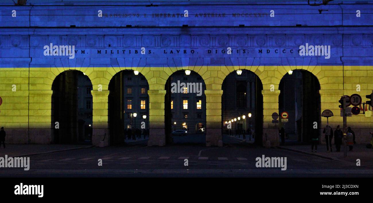Solidarietà austriaca con l'Ucraina. Hofburg cancello illuminato in colori ucraini bandiera. Foto Stock