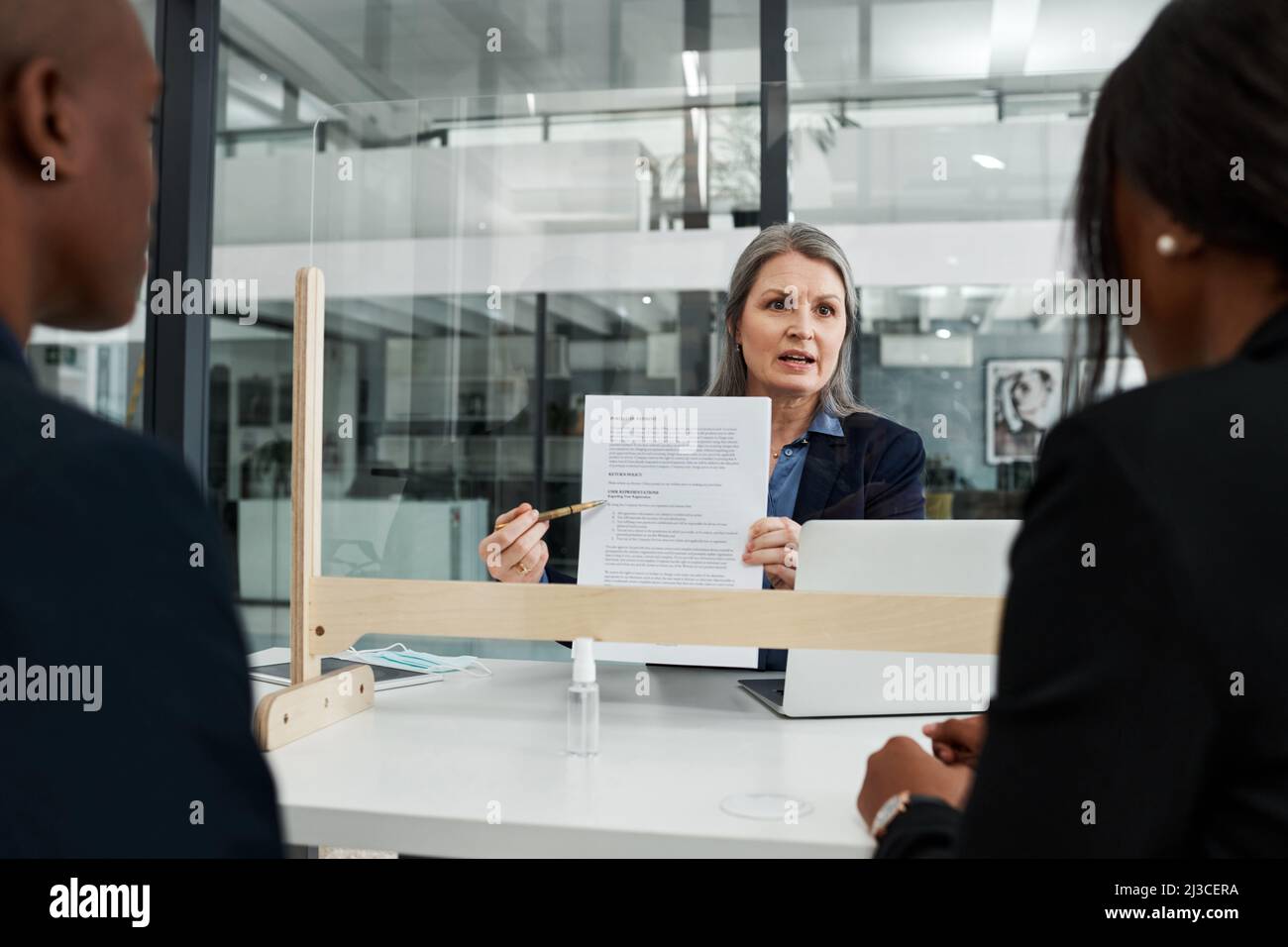 I controlli di sicurezza fanno parte del nostro protocollo. Shot di una donna d'affari matura che ha un incontro con una guardia starnuta in un ufficio moderno. Foto Stock