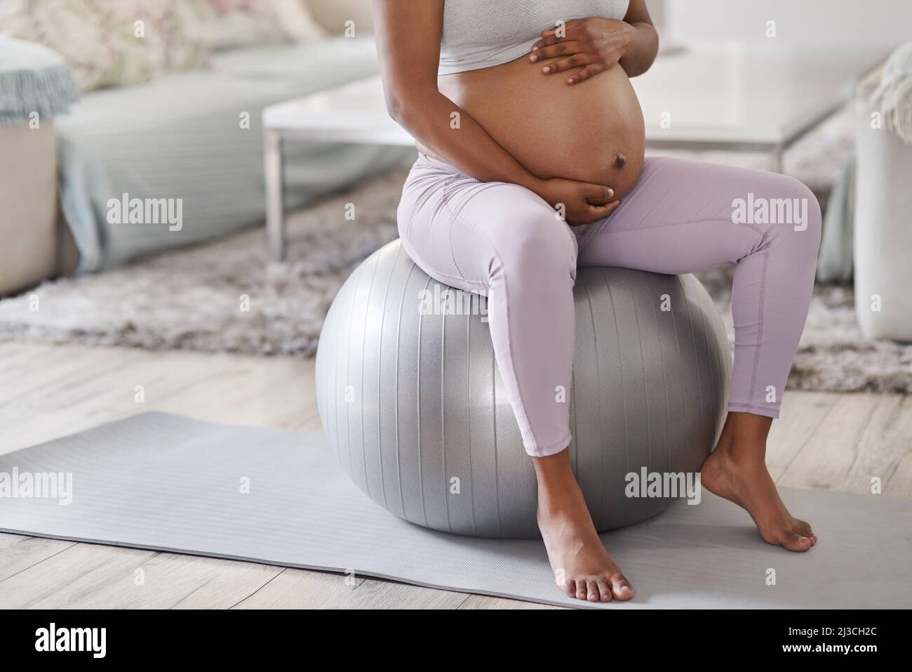 Ogni mom-to-be dovrebbe ottenere una sfera di stabilità. Scatto corto di una donna incinta seduta su una palla di stabilità a casa. Foto Stock