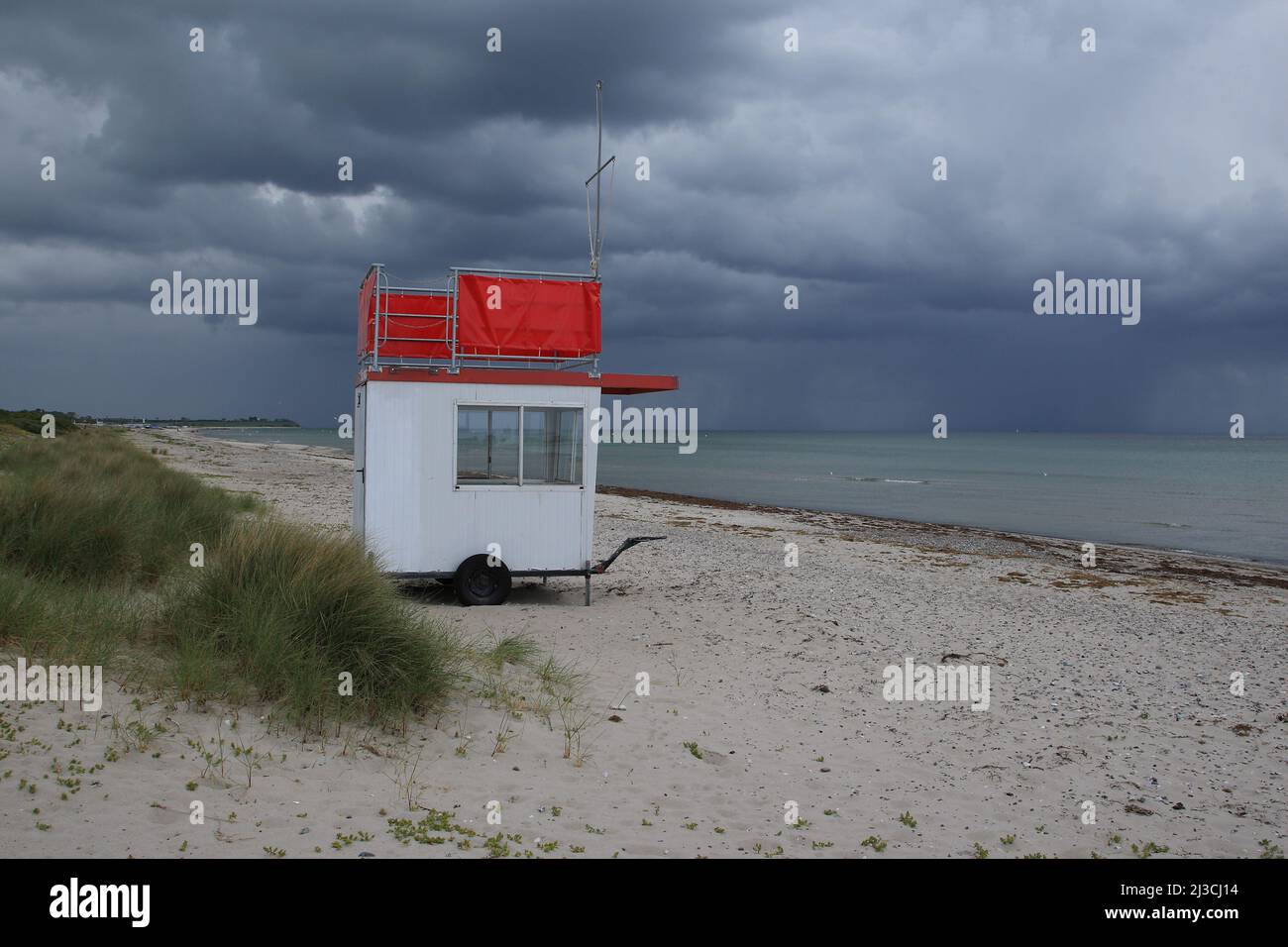 L'auto di osservazione del servizio di salvataggio dell'acqua si erge da sola sulla spiaggia del Mar Baltico, sulla quale si stanno raccogliendo nubi minacciose e scure di tempesta di tuore. Foto Stock