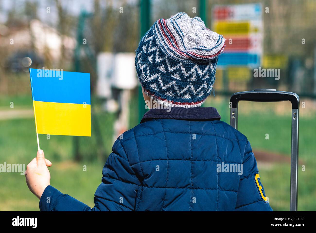 Bambino o capretto con abiti invernali, cappello e bandiera Ucraina, profilo del bambino è sulla bandiera. Guerra in Ucraina, causata da Putin e dalla Russia, rifugiati Foto Stock