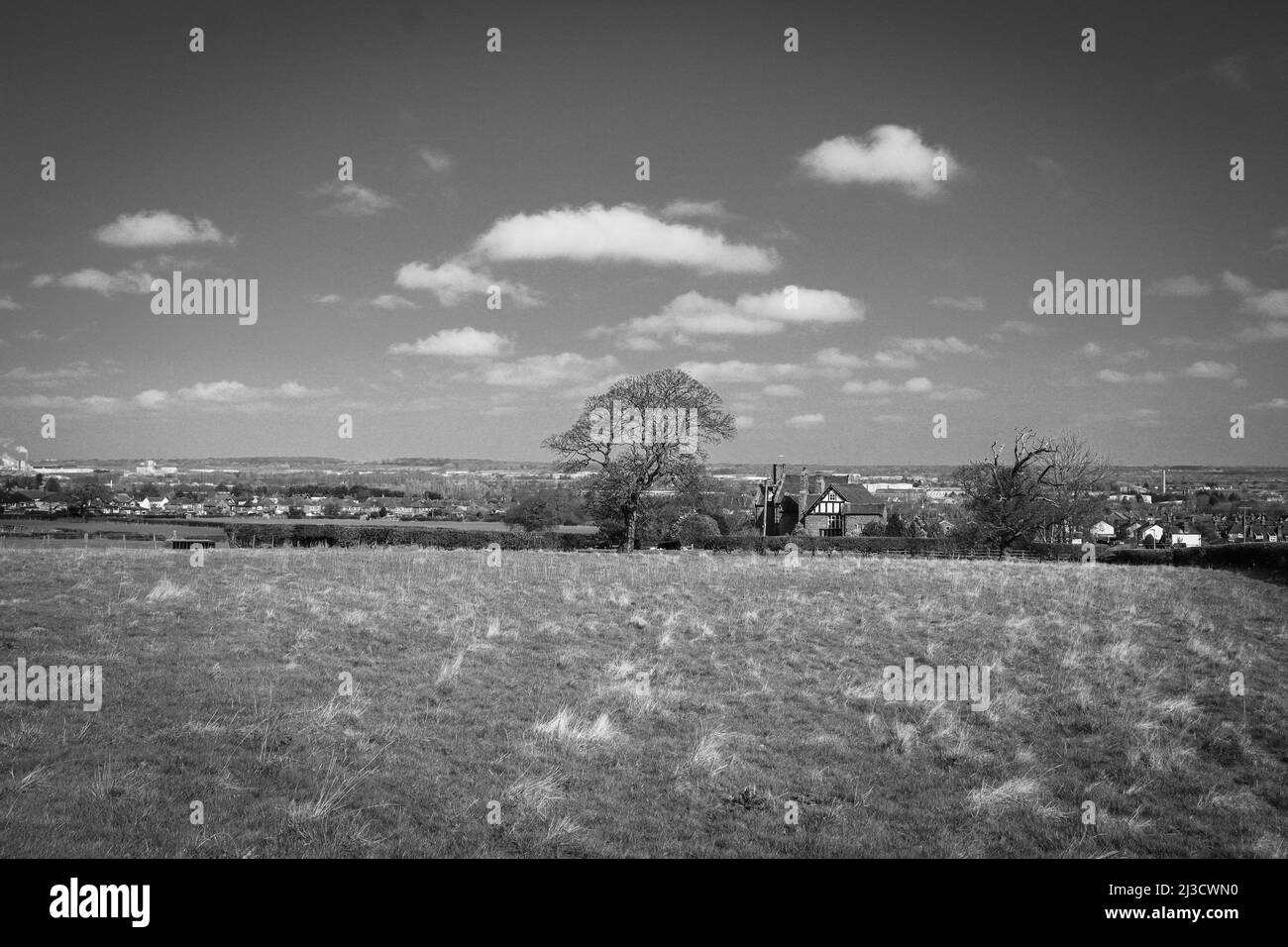 Vista su un campo, campagna aperta, con il cielo e le nuvole impressionanti, bianco e nero Foto Stock