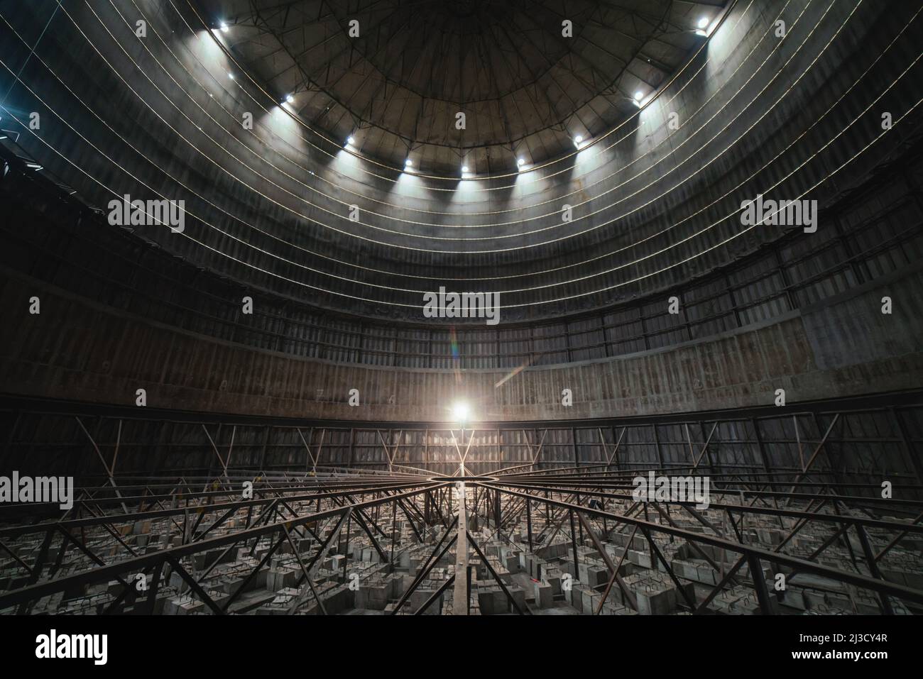 Interno di stanza rotonda scura con cupola e fioca lampada all'interno di uno stabilimento industriale derelitto Foto Stock