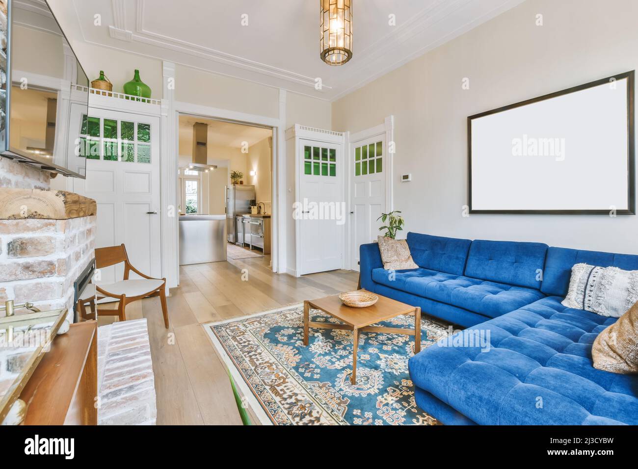 Comodo divano blu posto su tappeto contro la parete con TV e camino in  appartamento luminoso ed elegante con una porta aperta che conduce alla  cucina luminosa Foto stock - Alamy