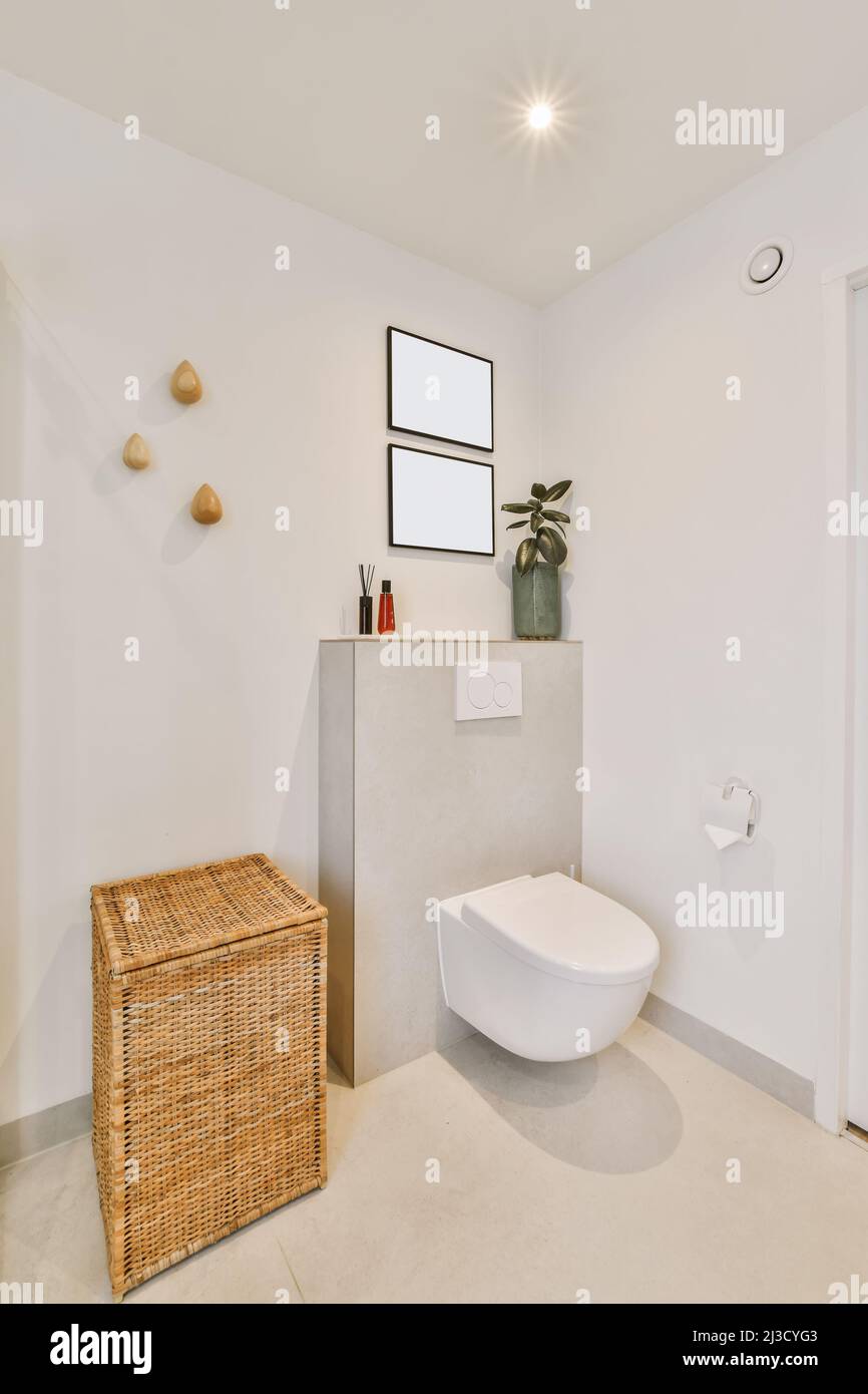 Interno di un piccolo bagno con wc in ceramica su pareti bianche in  appartamento vicino al cestino di rattan Foto stock - Alamy