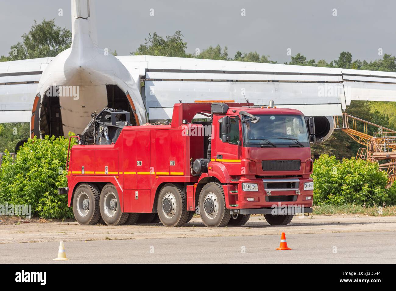 Un potente trattore semi-camion con carro di perforazione di grandi dimensioni traina l'aeroplano in background all'aeroporto Foto Stock