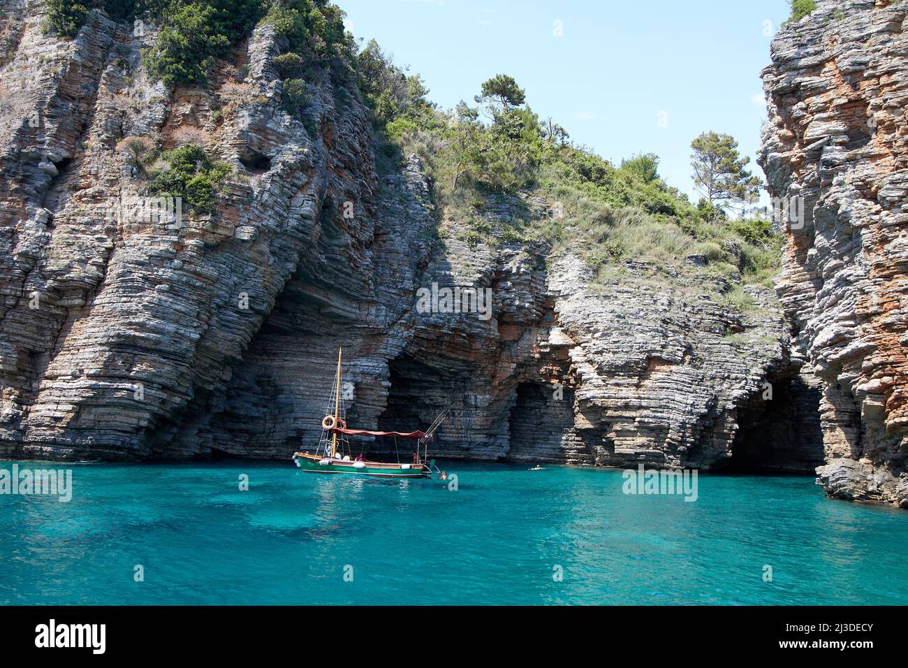 Laguna blu con barca da pesca vicino alla grotta nera Foto Stock
