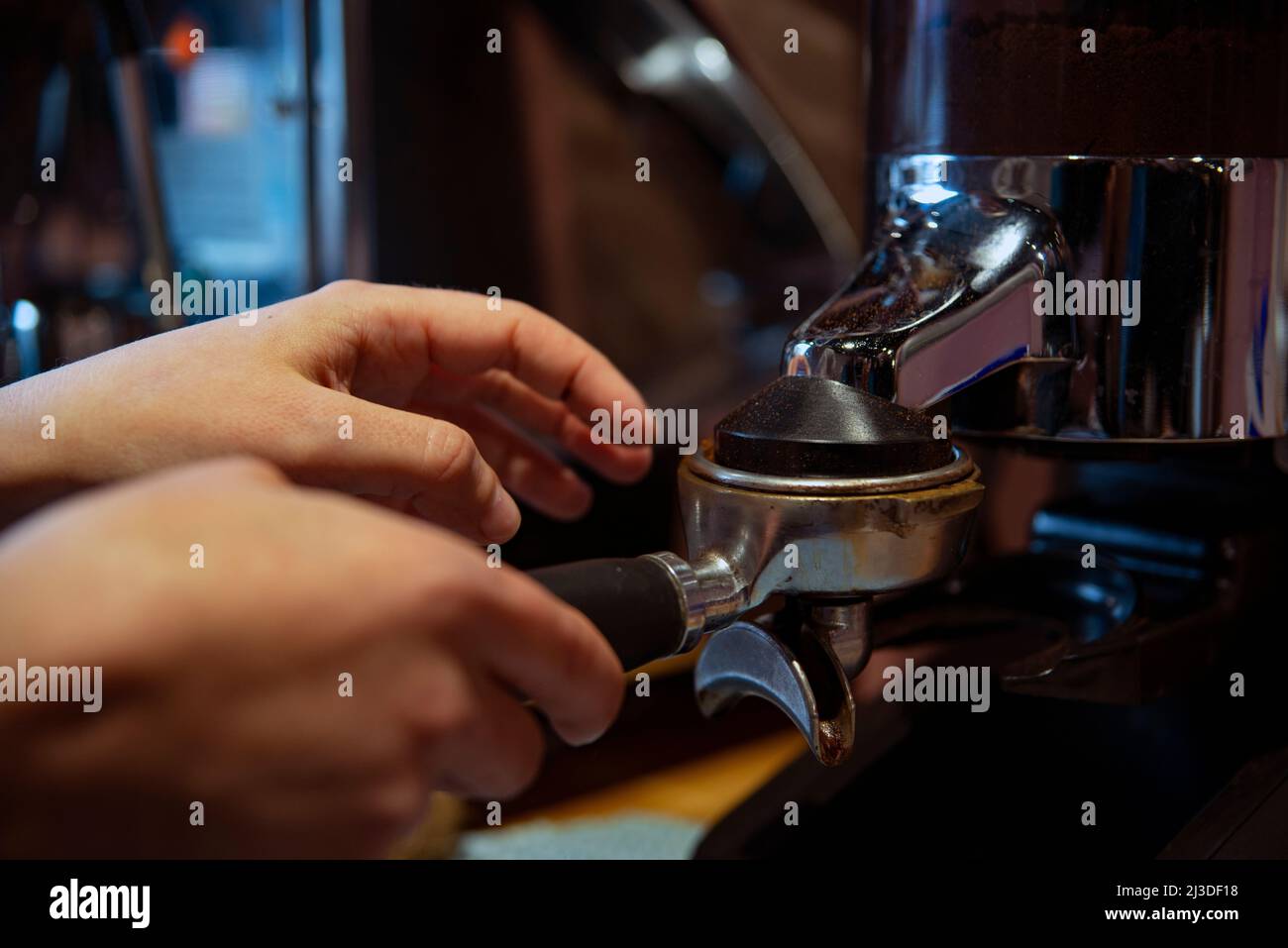 Il barista manomette i macinati di caffè in un portafilter, facendo espresso Foto Stock