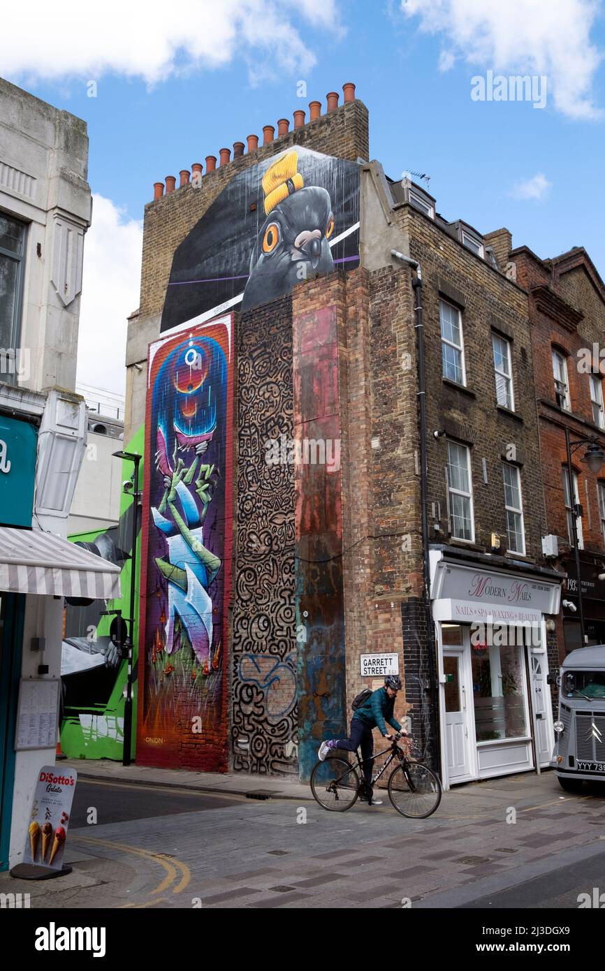 Ciclista e murales colorati su muro di edificio su Garrett St e Whitecross Street nel 2022 Londra EC1 Inghilterra Regno Unito Kathy DeWitt Foto Stock