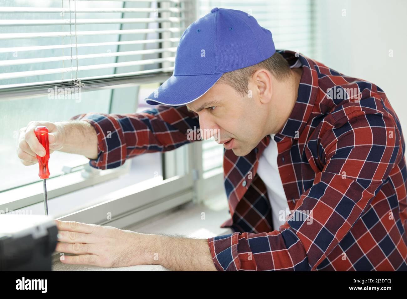 man avvita un cacciavite nella parete di legno Foto Stock