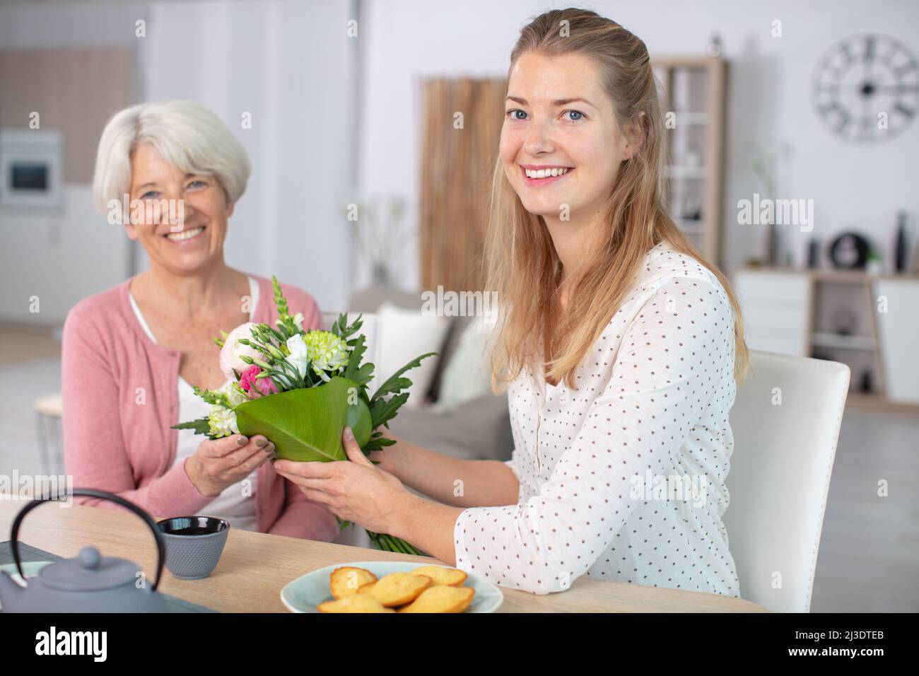 la figlia dà i fiori alla madre anziana Foto Stock