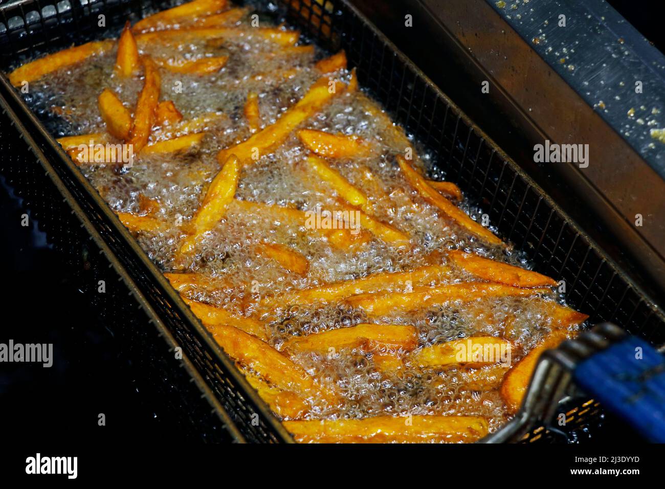 patatine fritte (patate dolci) in un cestino di frittura, cibi malsani e spazzatura Foto Stock