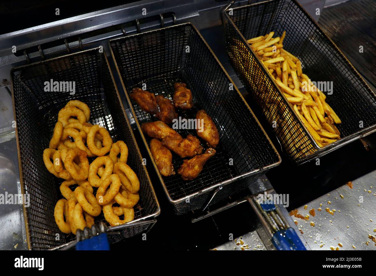 snack fritti in un cestino di frittura grasso, patatine fritte, anelli di cipolle e ali, ecc. Foto Stock