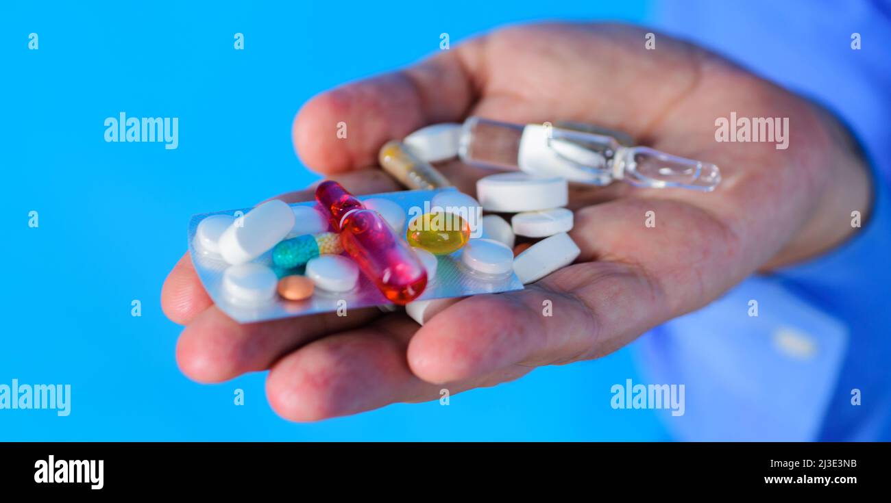Mani dell'uomo con pillole diverse prescritte dal medico. Trattamenti e assistenza sanitaria. Concetto di medicina. Foto Stock