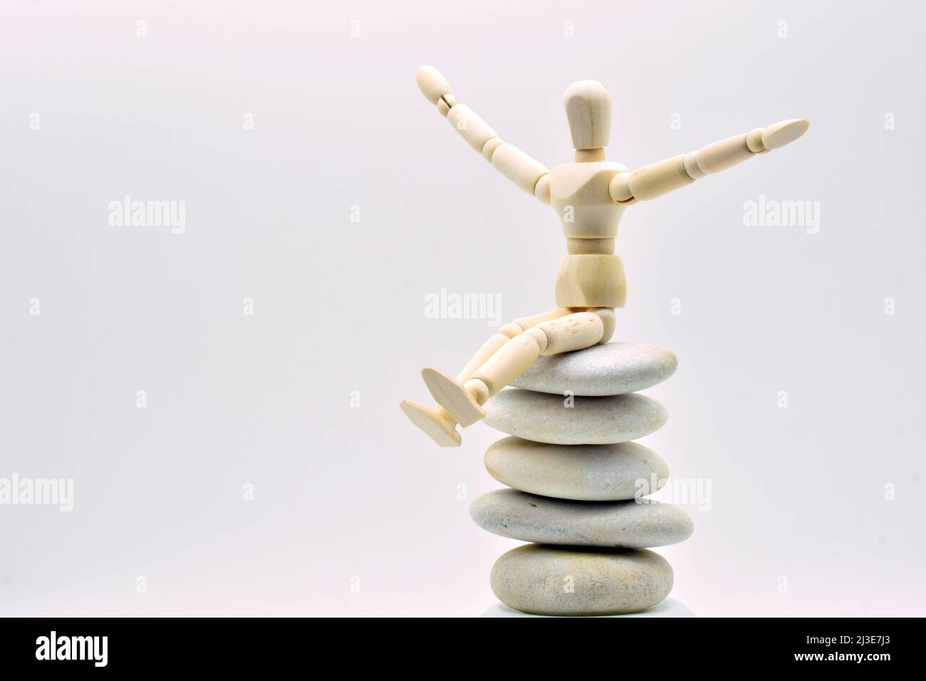 Muñeco articulado de madera sentado en una pila de piedras zen Foto Stock