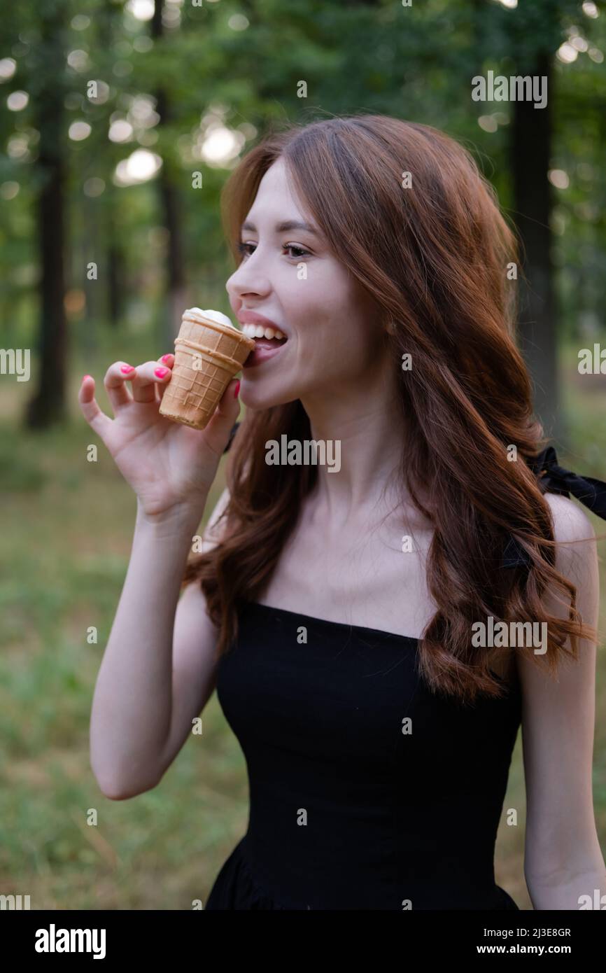 Sorridente allegra brunetta ucraina giovane donna mangiare gelato all'aperto. Foto Stock