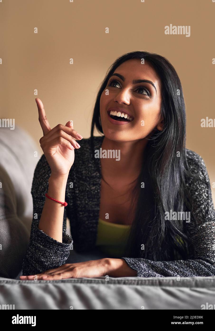 Ho capito. Scatto di una giovane donna attraente che guarda ispirato mentre si trova sul suo divano a casa. Foto Stock