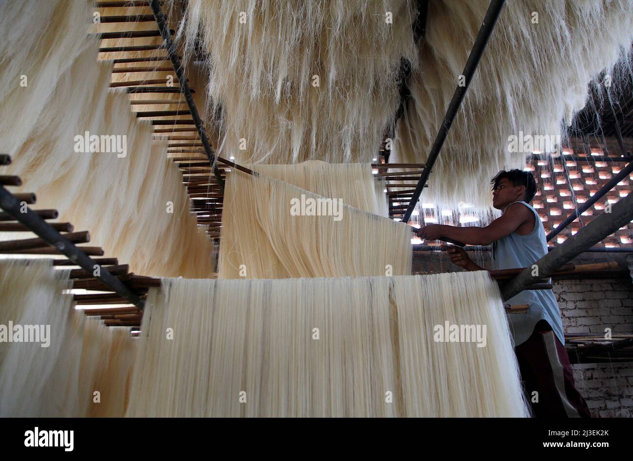 Un operaio prepara vermicelli che viene utilizzato per preparare piatti dolci tradizionali consumati popolare durante il mese santo del Ramadan, in Prayagraj, India. Foto Stock