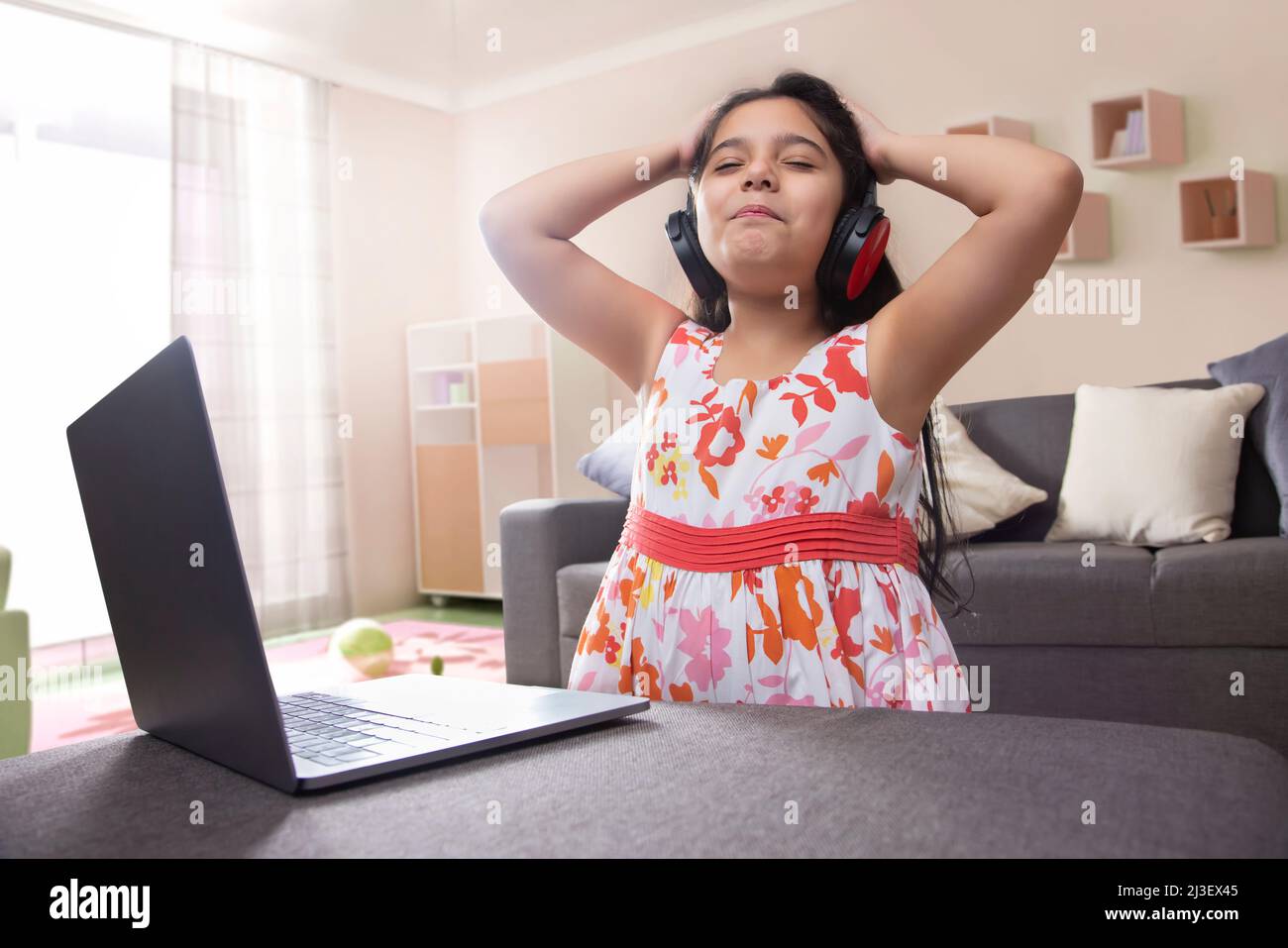Ragazza che ascolta musing sul portatile con occhi chiusi e mani sulla testa Foto Stock