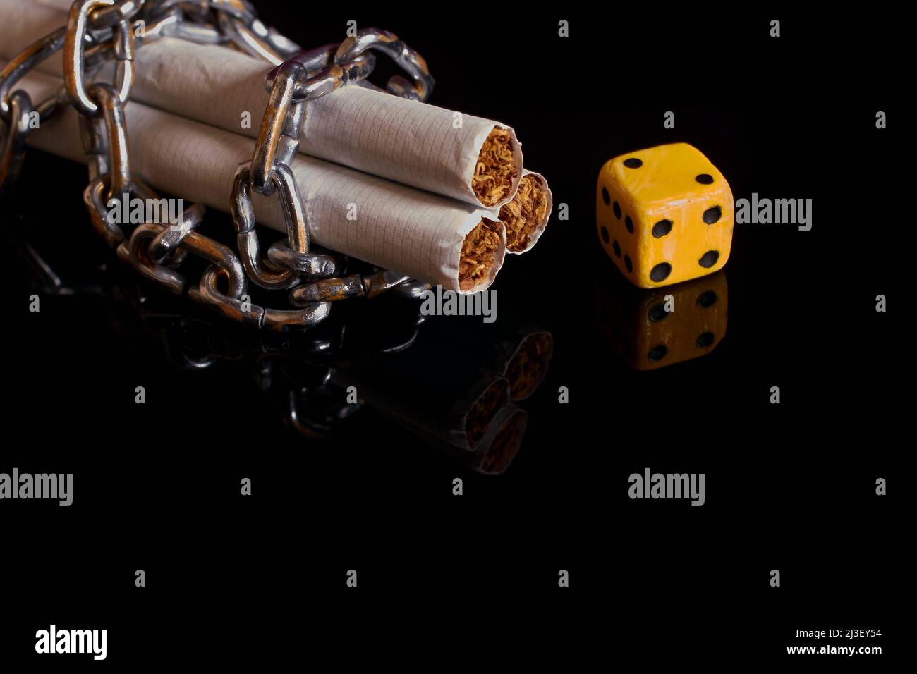 Nicotina e dipendenza da gioco d'azzardo. Sigarette, riavvolte da una catena e da un dado Foto Stock