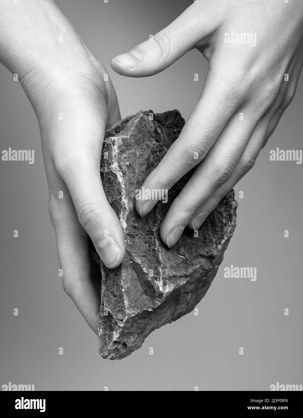 Donna mani che tengono pietra. Concetto di sensibilità al tocco. Ottenere informazioni tattili e termiche dall'ambiente. Materiale solido, ruvidità superficiale. Bianco e nero . Foto di alta qualità Foto Stock