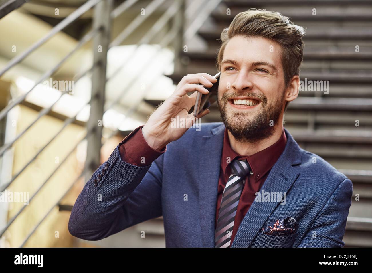 HES tutto su stile e stato. Ritratto di un giovane uomo d'affari felice usando il suo telefono mentre fuori in città. Foto Stock