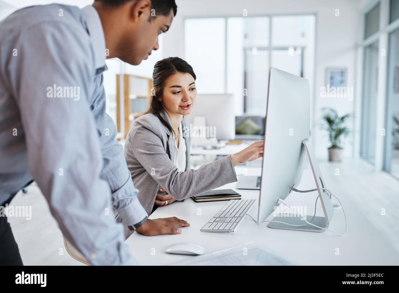 Tecnologia che corrisponde alla loro azienda orientata al target. Shot di un giovane uomo d'affari e di una donna d'affari che usa un computer in un ufficio moderno. Foto Stock