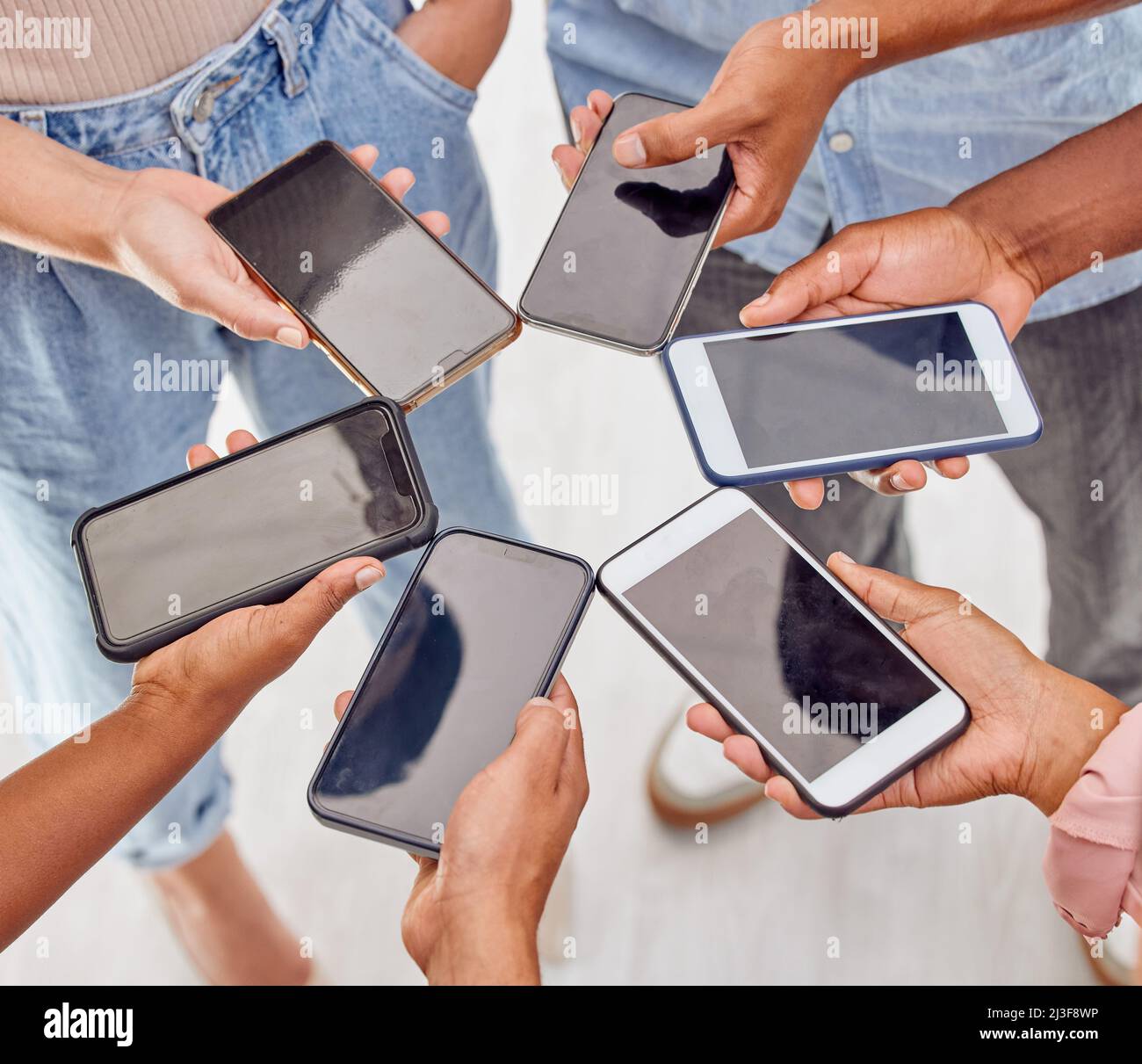Connesso come gruppo. Foto di un gruppo di persone irriconoscibili che si trovano in un cerchio e utilizzano dispositivi digitali in ufficio. Foto Stock