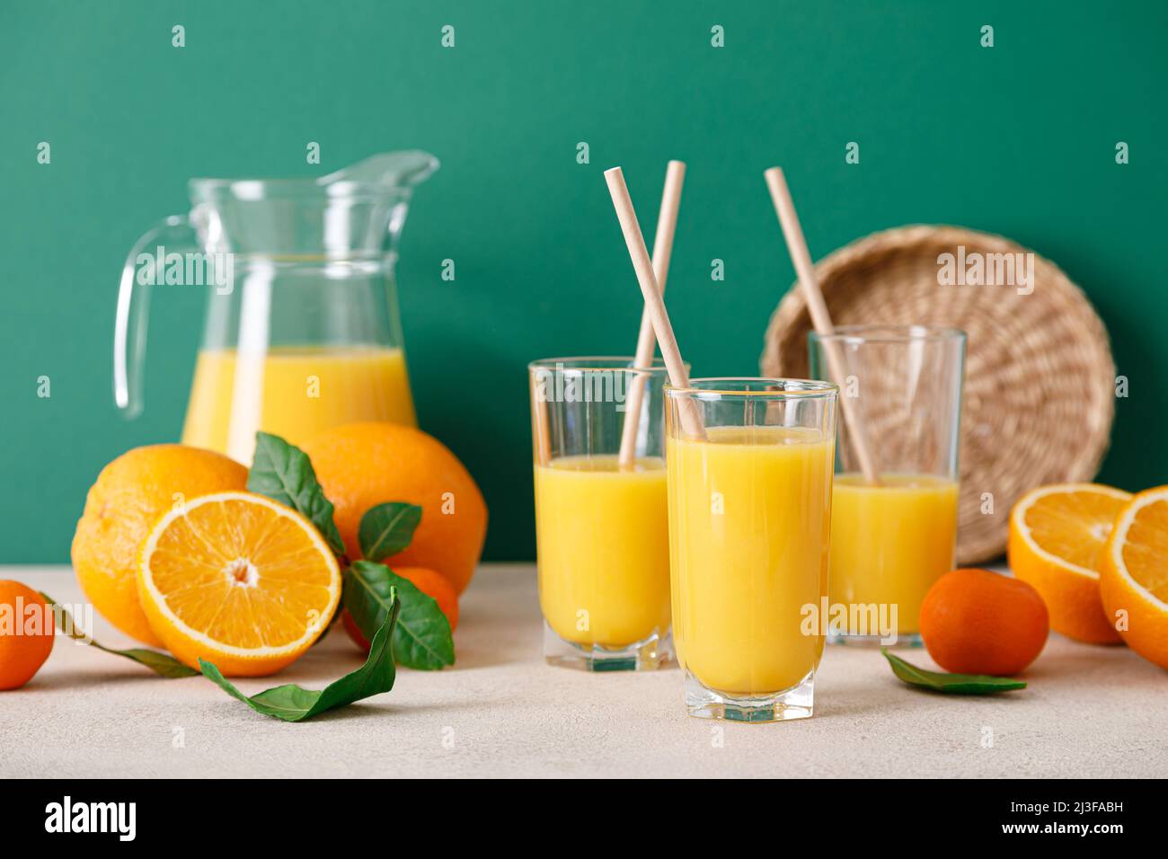 Succo d'arancia appena spremuto in un bicchiere con paillette e frutta fresca con foglie, bevanda sana, concetto di vitamina c, vista frontale Foto Stock