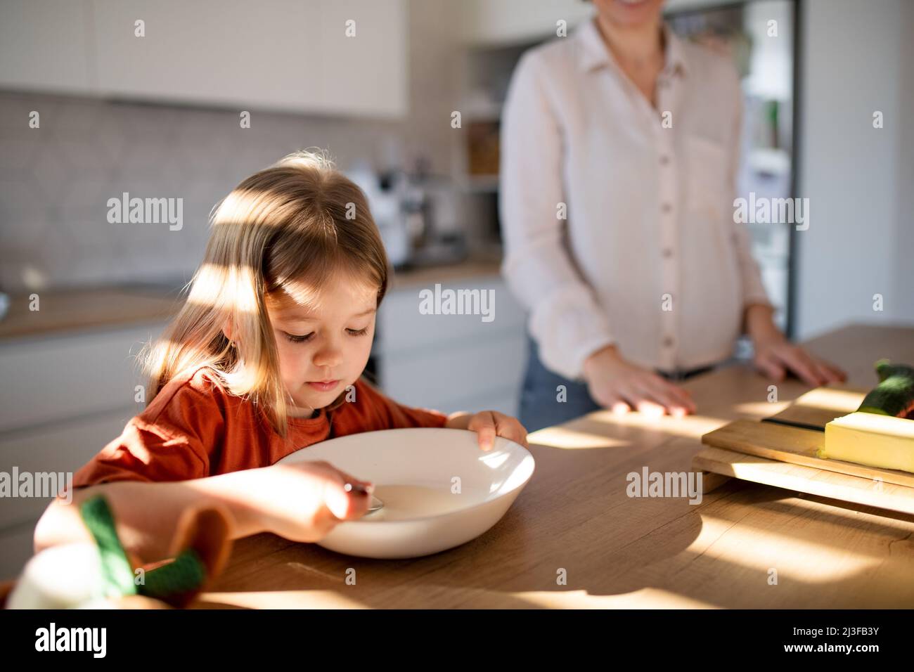 Piccola ragazza che ha fatto colazione con la madre in cucina. Foto Stock