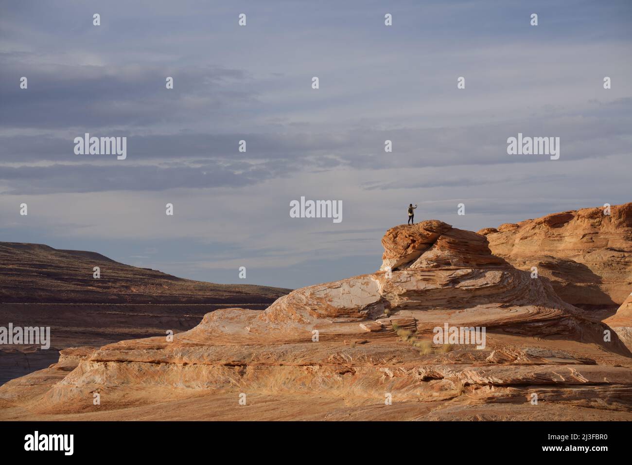 Ragazza che prende un selfie su una cima di scogliera, le catene, pagina, Arizona. Scogliere di arenaria, lago Powell e cielo nuvoloso. Foto Stock