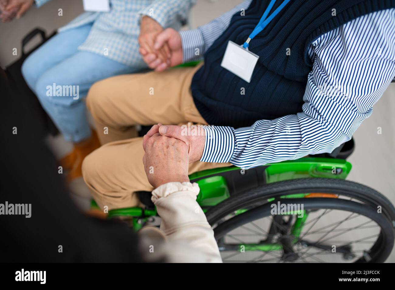 Primo piano dell'anziano seduto in sedia a rotelle durante la sessione di terapia di gruppo. Foto Stock