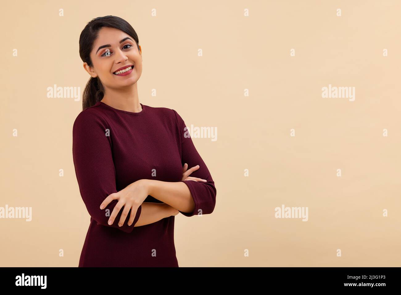 Ritratto di una giovane donna felice in posa con le braccia incrociate Foto Stock