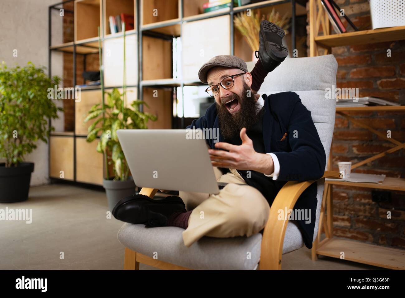 Ritratto di giovane uomo barbuto, yoga felice facendo yoga esercizio su poltrona in ufficio a tempo di lavoro. Concetto di business, stile di vita sano, sport Foto Stock