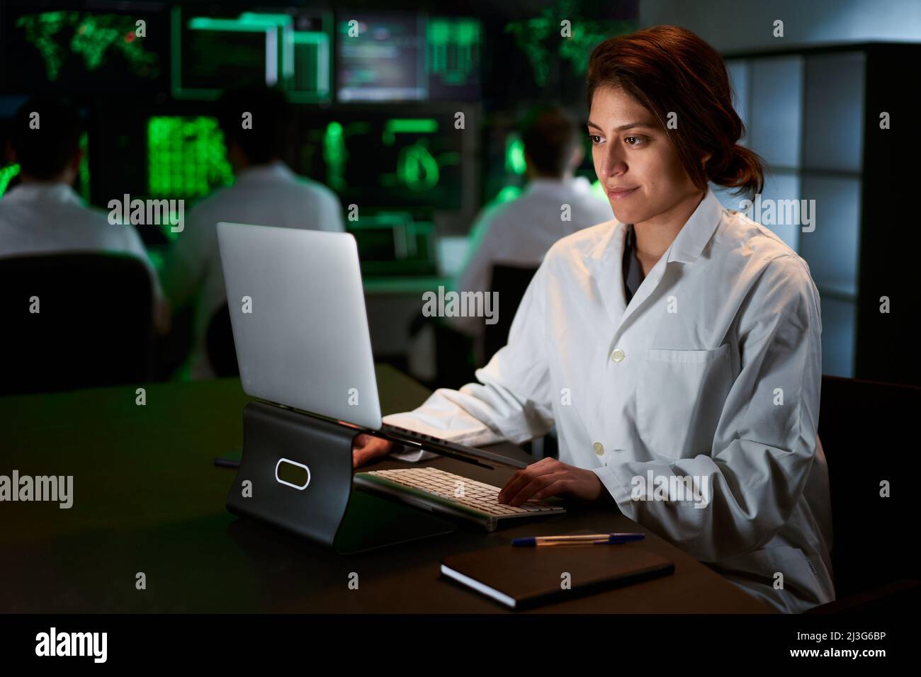 Scienziata di ricerca medica femminile che usa il computer portatile. Neurologo risolvere i puzzle della mente e del cervello. In laboratorio con schermi multipli Foto Stock