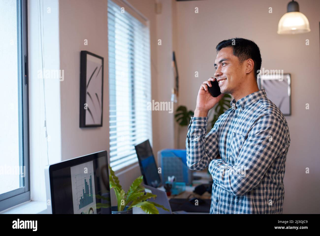 Un uomo si alza nel suo ufficio per una telefonata, guardando i grafici dei risultati Foto Stock