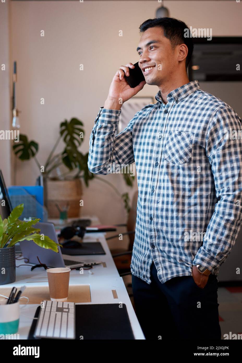 Un uomo si alza nel suo ufficio per una telefonata, guardando i grafici dei risultati Foto Stock