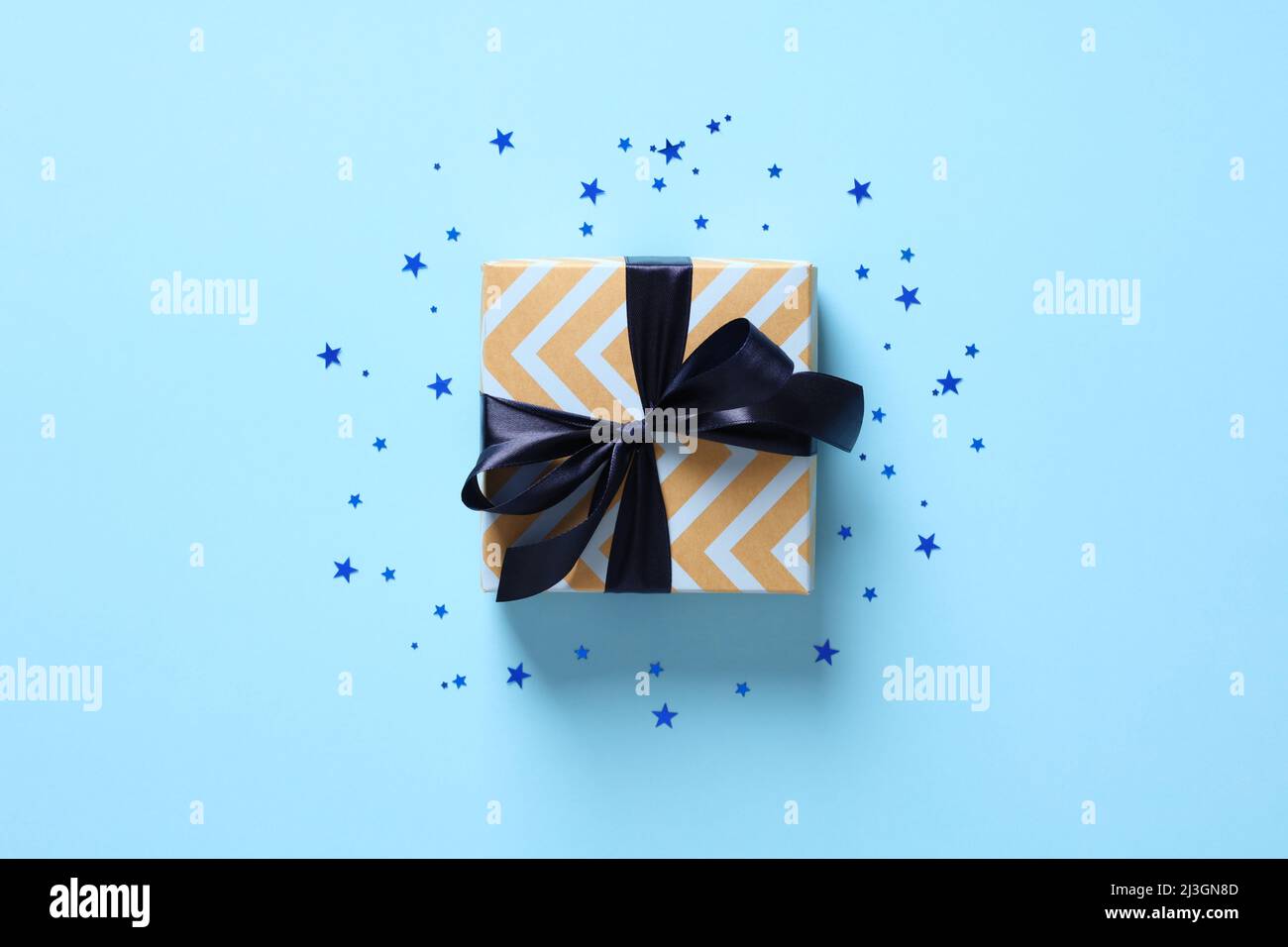 Confezione regalo vintage con arco a nastro blu su sfondo blu pastello con stelle a confetti. Buon giorno dei Padri, concetto di compleanno. Foto Stock