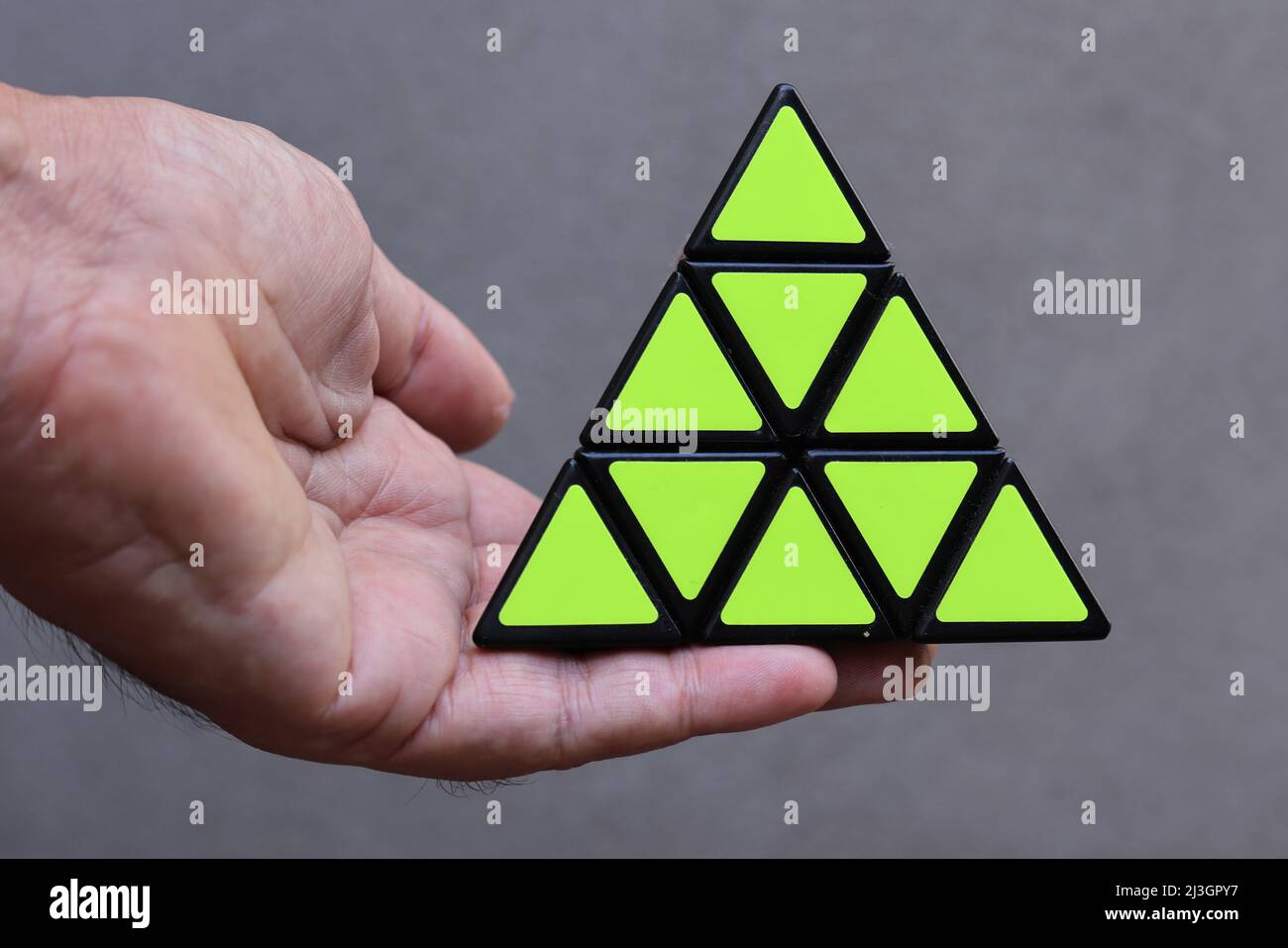 Un puzzle a forma di triangolo in una mano Foto Stock