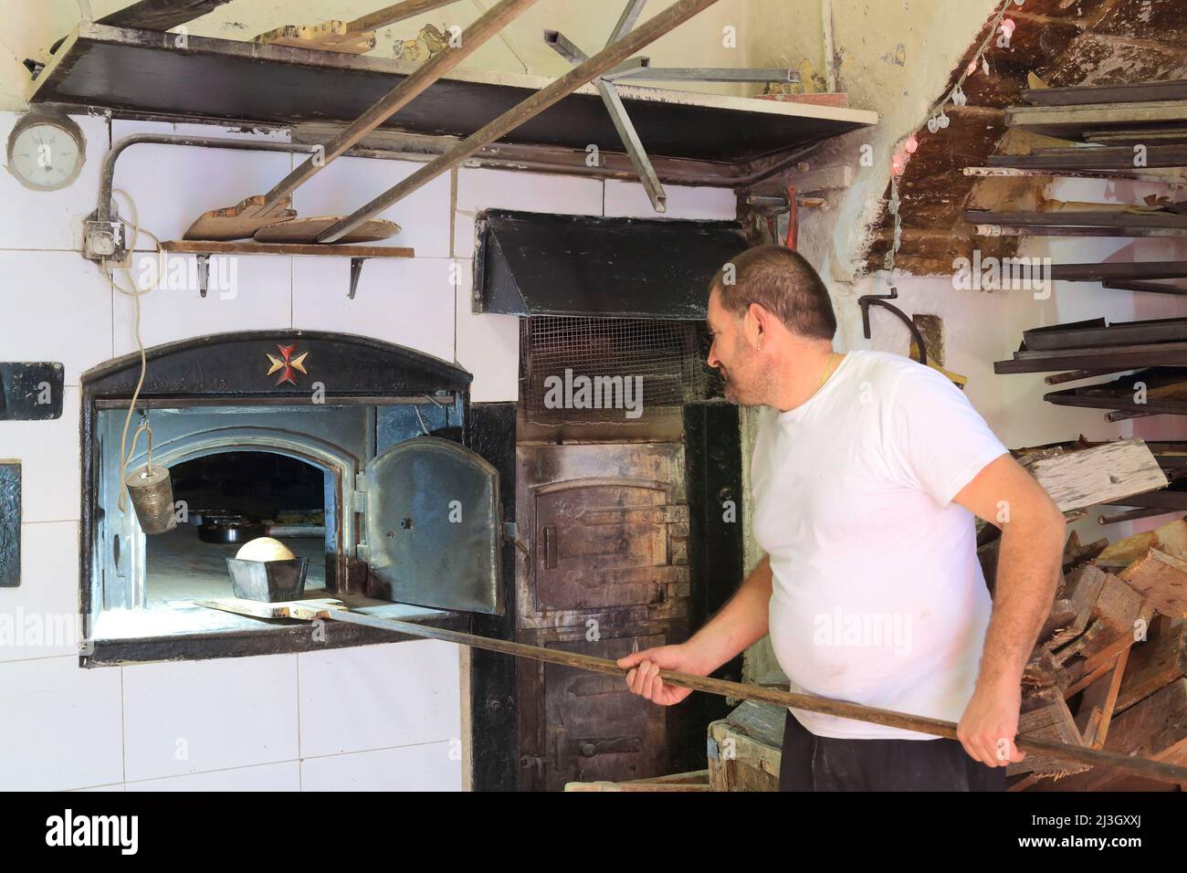 Malta, Haz Zebbug, panetteria di tal-conti secolare, Anton conti mettere il suo pane in un forno a legna Foto Stock