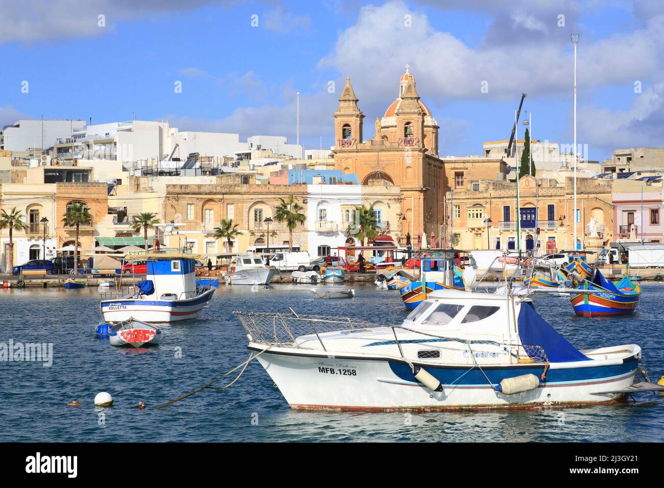 Malta, Marsaxlokk, porto di pesca fondato dai Fenici nel 9th a.C. JC con sullo sfondo la facciata della chiesa parrocchiale di nostra Signora di Pompei (1897) Foto Stock