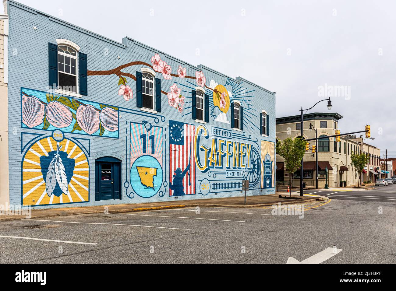 GAFFNEY, S.C. USA-2 APRILE 2022: Murale dipinto in centro-colorato che mostra i simboli della città, e uno storico edificio angolare su Limestone Street. Foto Stock