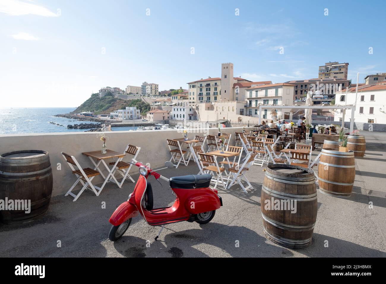 Una Vespa rossa d'epoca parcheggiata all'esterno del caffè vicino al porto, il simbolo dello scooter italiano, Piombino, Toscana, Italia Foto Stock