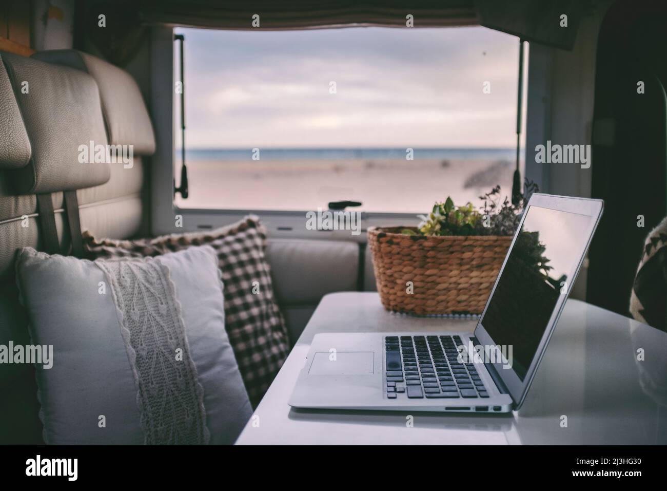 Computer portatile in camper sulla spiaggia, concetto - vacanza, flessibilità, libertà, lavoro intelligente, indipendenza, nomadi digitali Foto Stock
