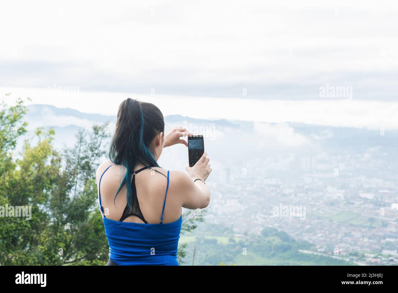 influencer ragazza che crea contenuti per i suoi social network, mentre escursioni. donna latina in cima a una montagna che registra un video e stabilizza il mo Foto Stock