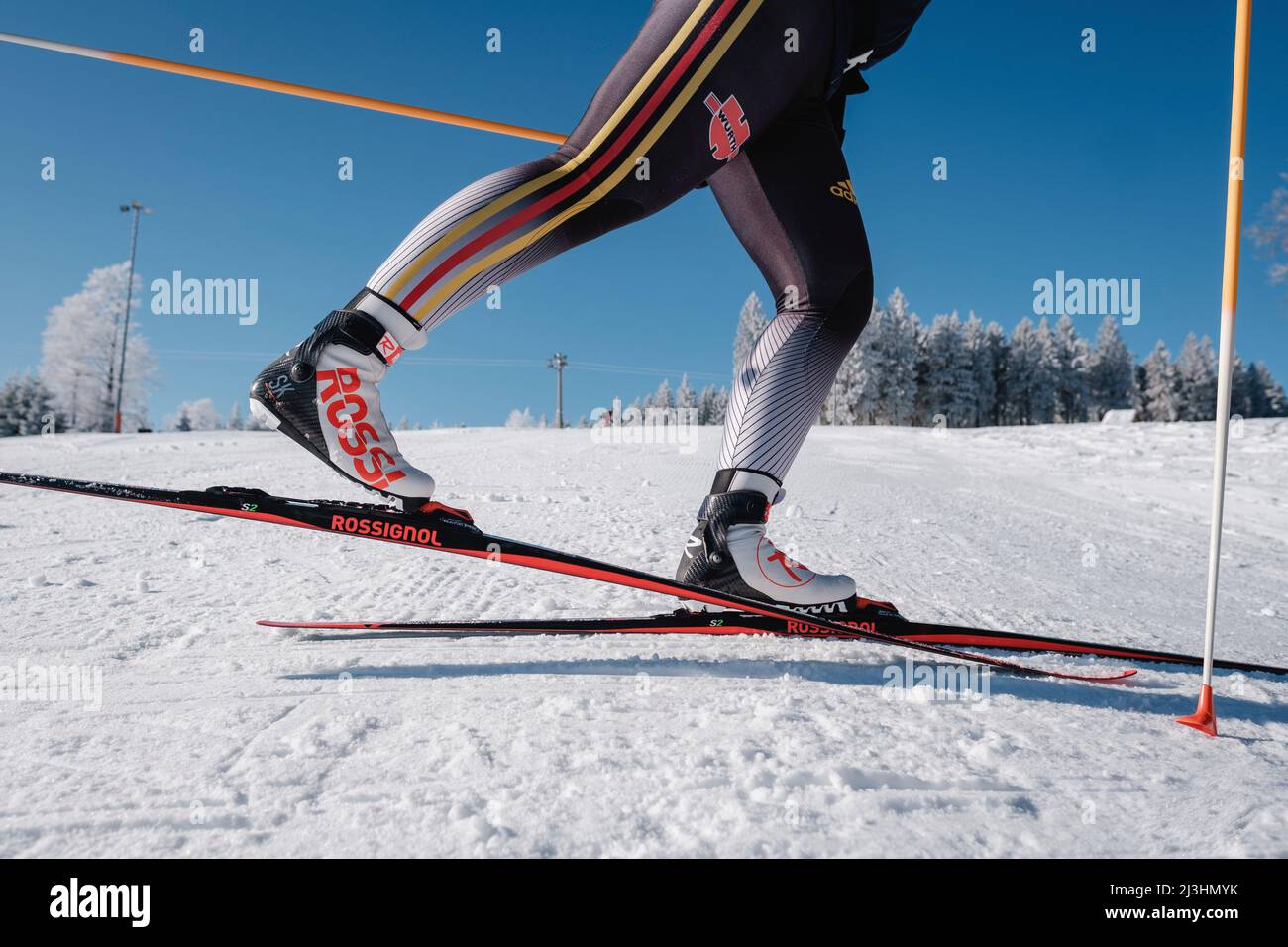 Sci di fondo, primo piano di atleta con sci, scarponi e racchette, neve collina sullo sfondo Foto Stock